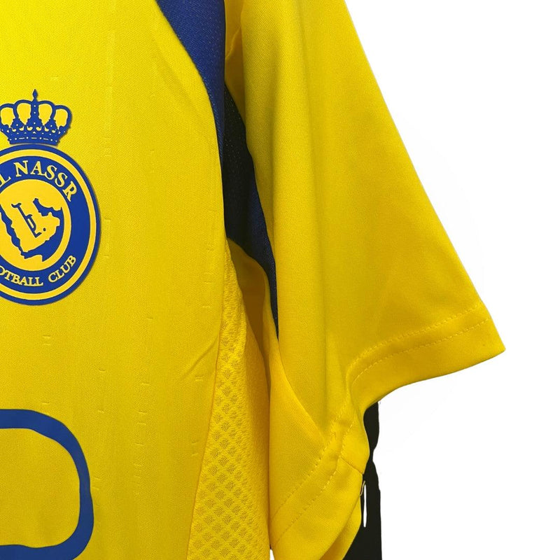 camisa-al-nassr-titular-I-home-24-25-amarelo-azul-gola-v-versão-torcedor-manga-curta-cabide-fundo-branco-cristiano-ronaldo-árabe