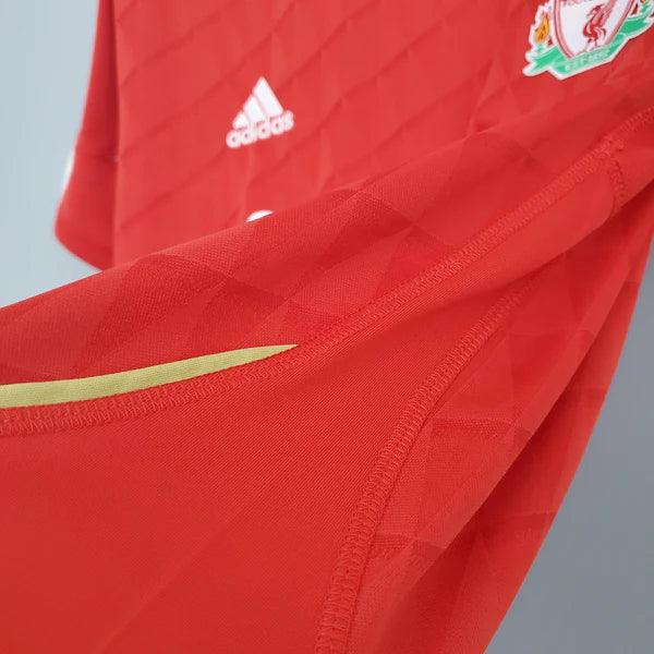 camisa-liverpool-titular-I-retrô-2010-2011-vermelho-gola-redonda-cabide-fundo-branco-listras-brancas-adidas-detalhe-dourado