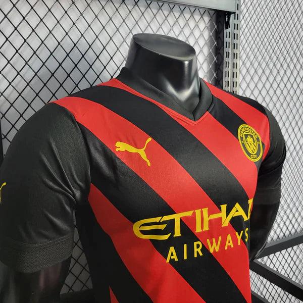 camisa-manchester-city-away-22-23-versão-jogador-puma-vermelho-preto-amarelo-manequim-fundo-grade-gola-v