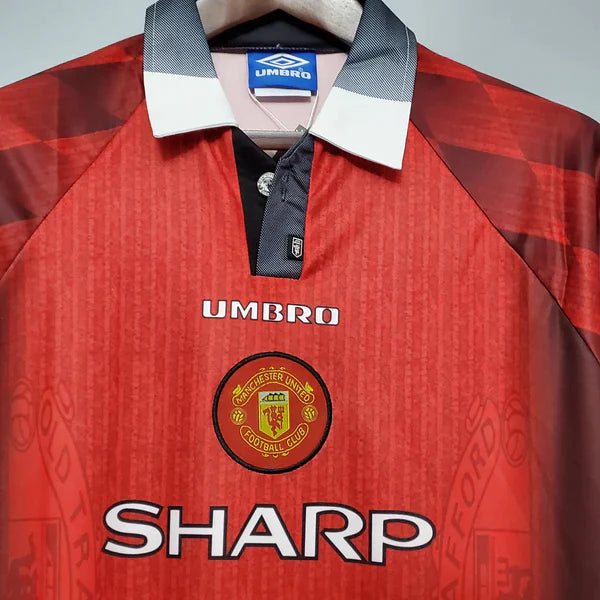 camisa-manchester-united-retrô-titular-1-home-1996-vermelho-preto-gola-polo-manga-curta-fundo-branco-pendurada-cabide